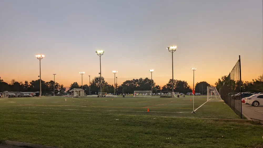 La cancha de césped artificial iluminada de Blue Ash Sports Center al atardecer